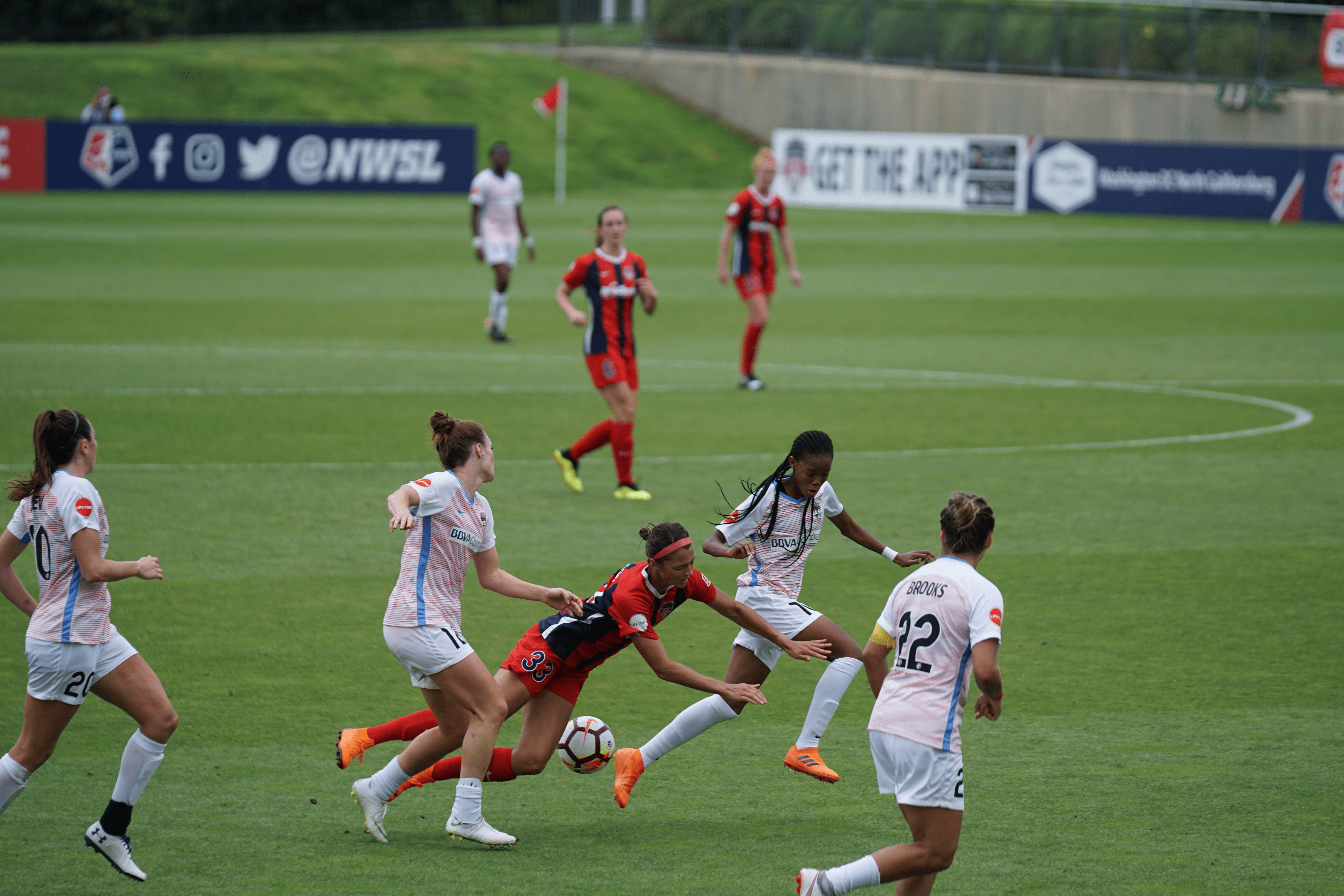 Women playing soccer on an outdoor pitch.